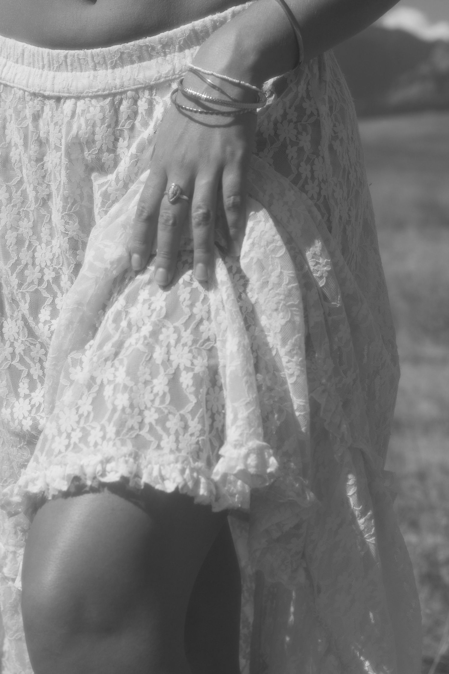 Close-up details of delicate white lace fabric on a dress moving in natural light.