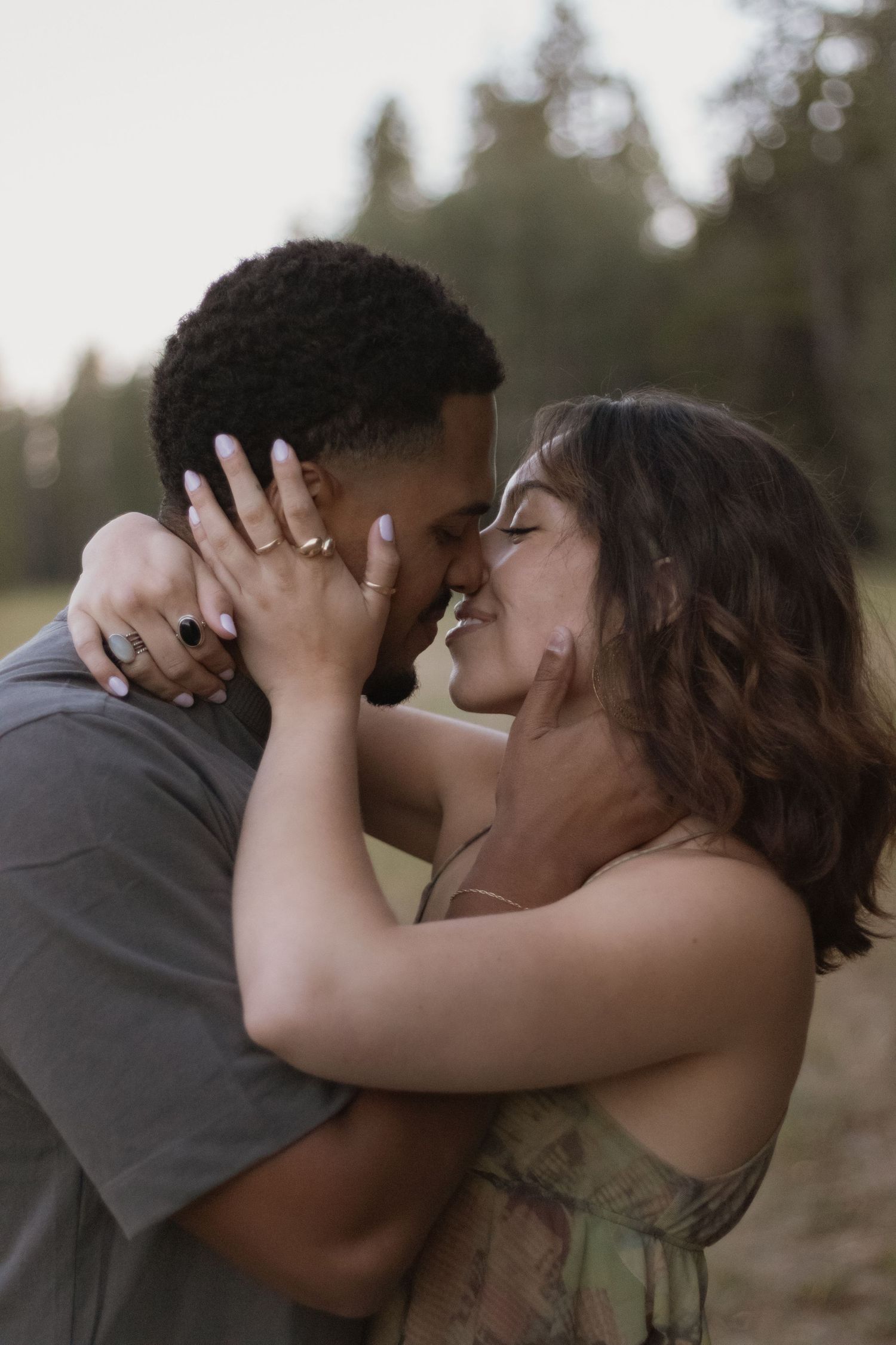 Romantic couple sharing an intimate kiss in a natural outdoor setting.