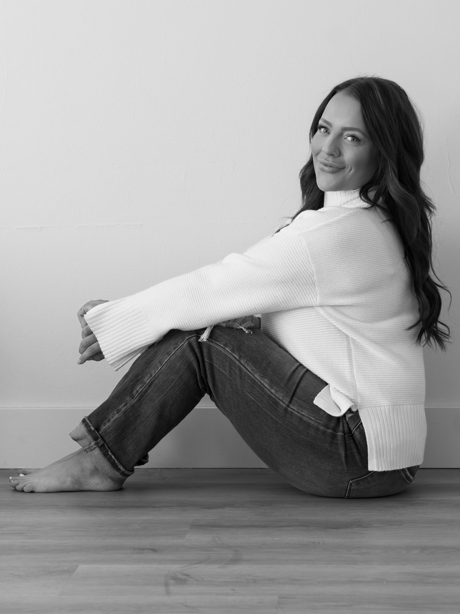 A series of black and white photos showing someone in a white sweater and jeans lying on a wooden floor.