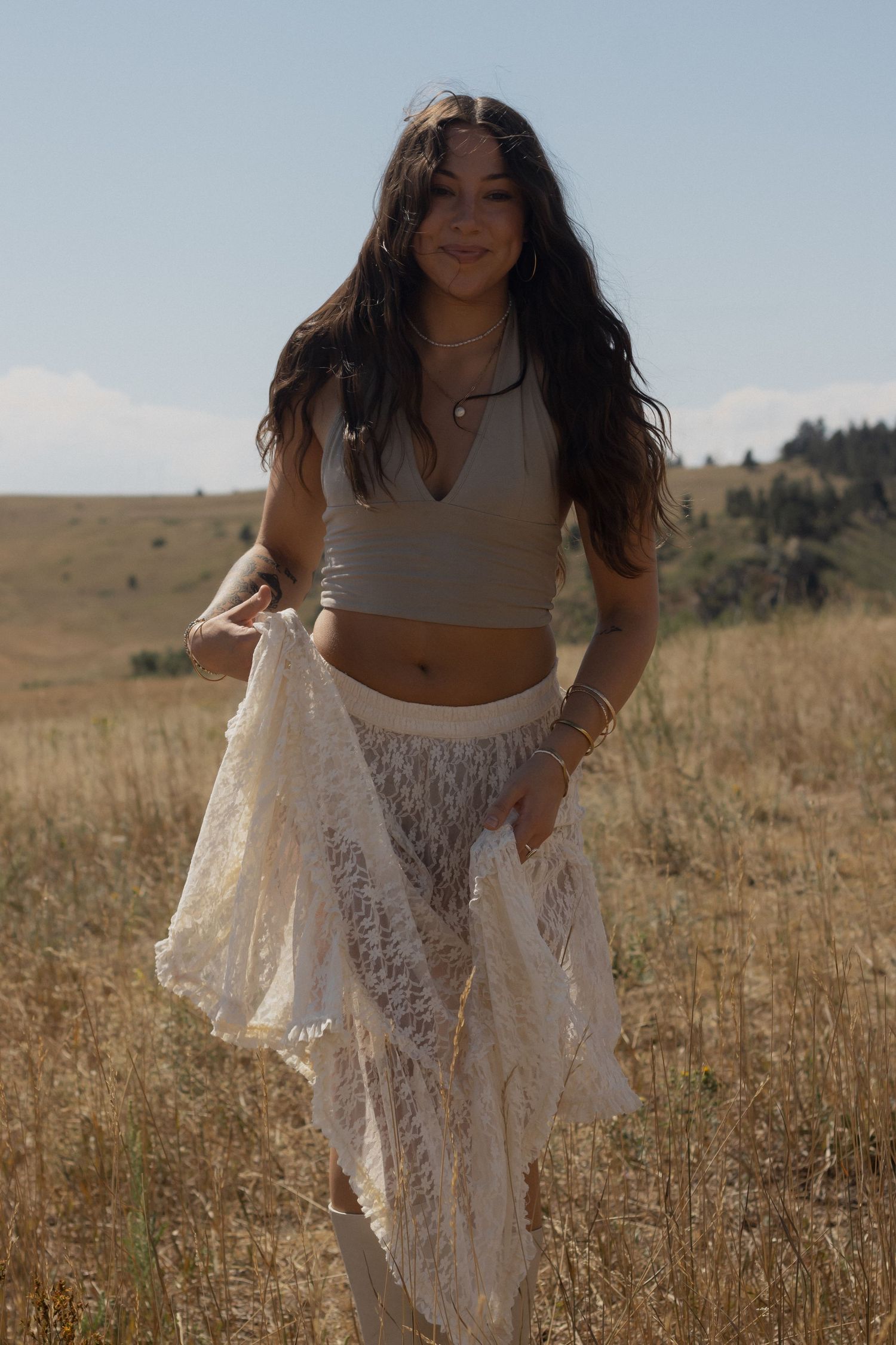 A bohemian style portrait in a golden field featuring white lace and a crop top.