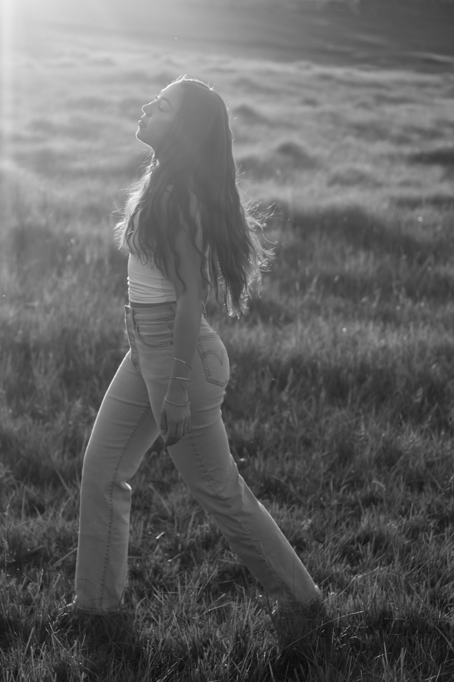 Silhouette walking through a sunlit grassy field at dusk.