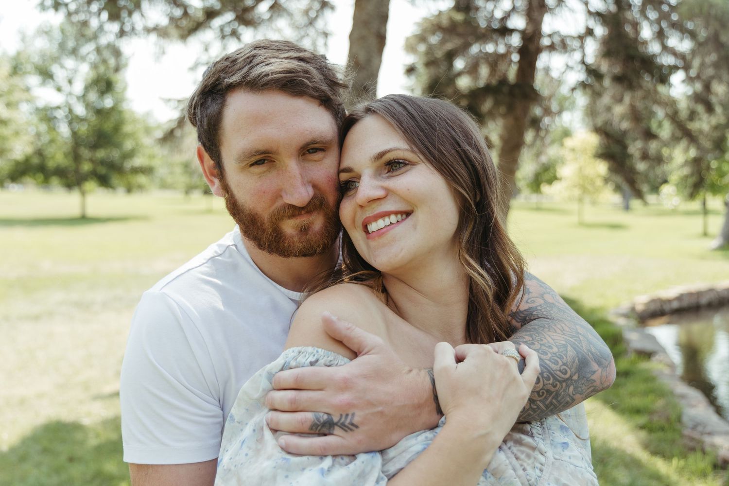 Couple embracing outdoors in a sunny natural setting.