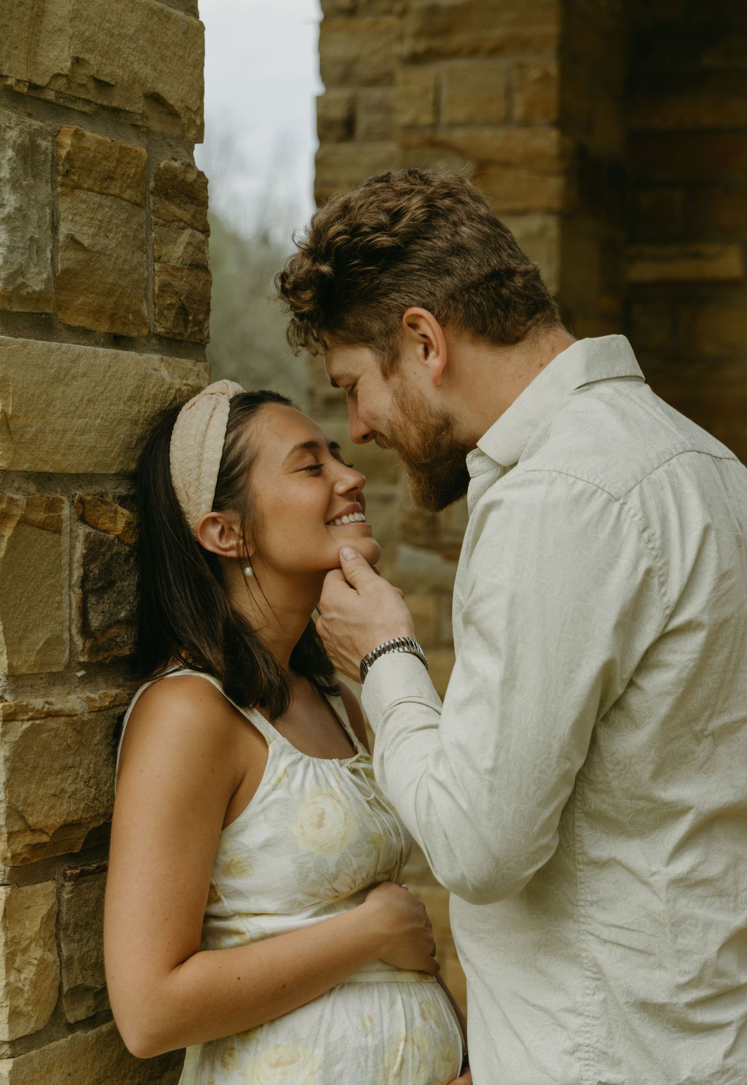 A sweet moment shared between a couple against a rustic stone wall background.
