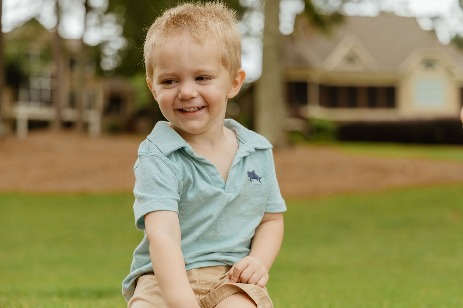 Smiling child in casual summer attire sitting outdoors.
