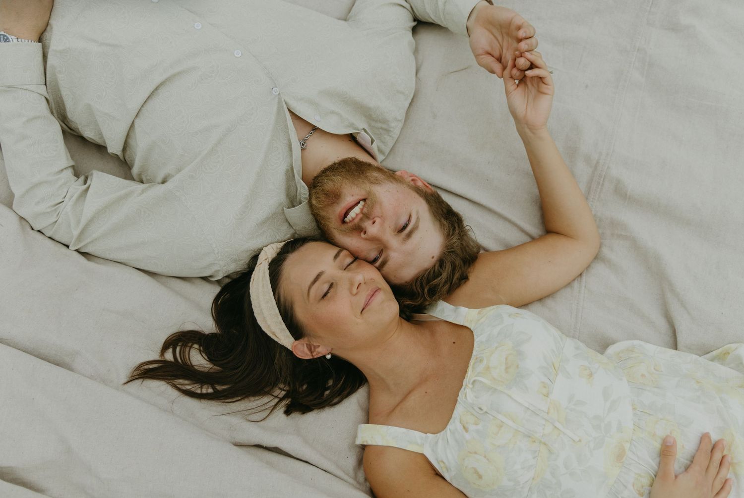 A couple relaxes on a blanket outdoors sharing happy moments together.