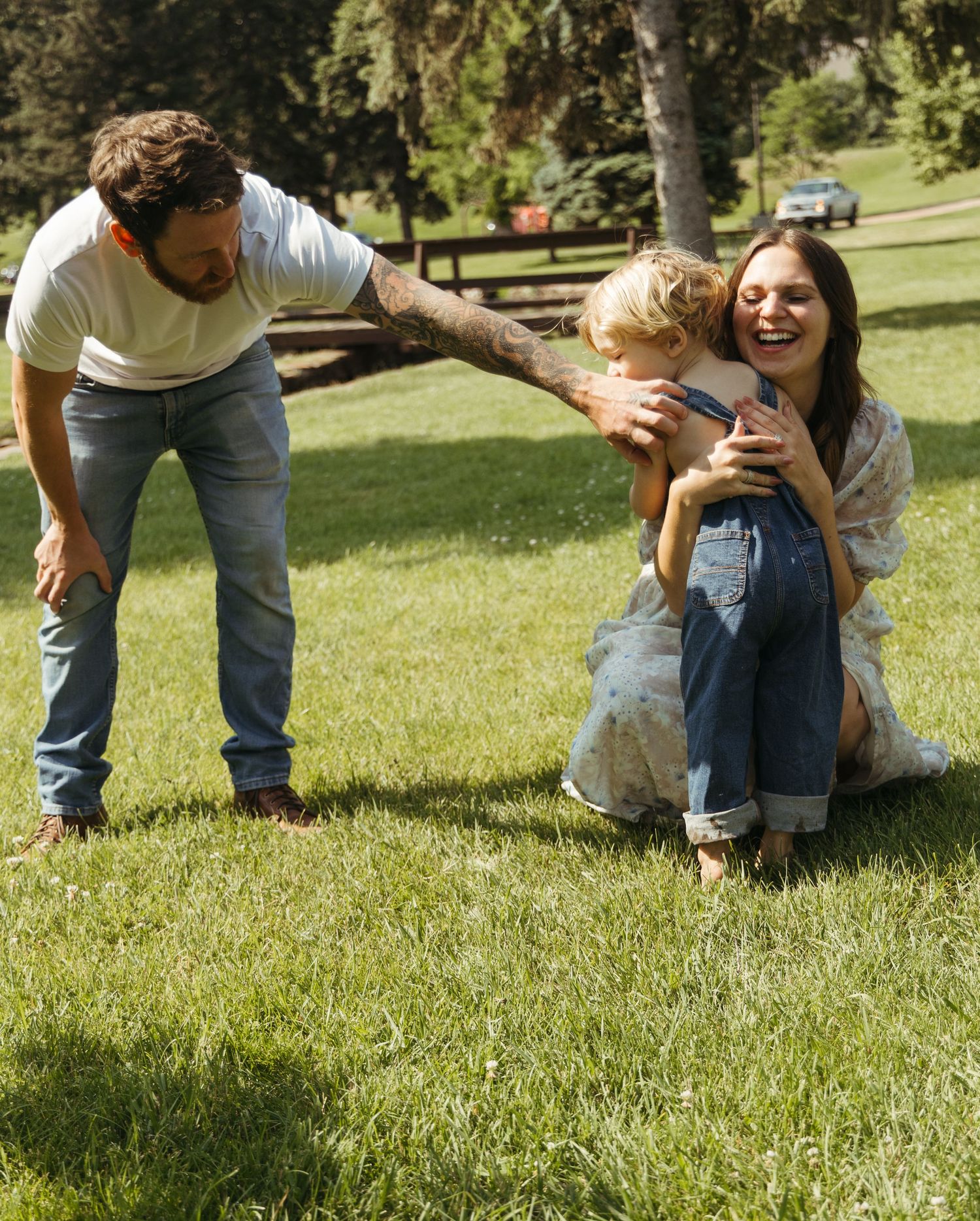 Playful family interactions on green grass during outdoor photoshoot.