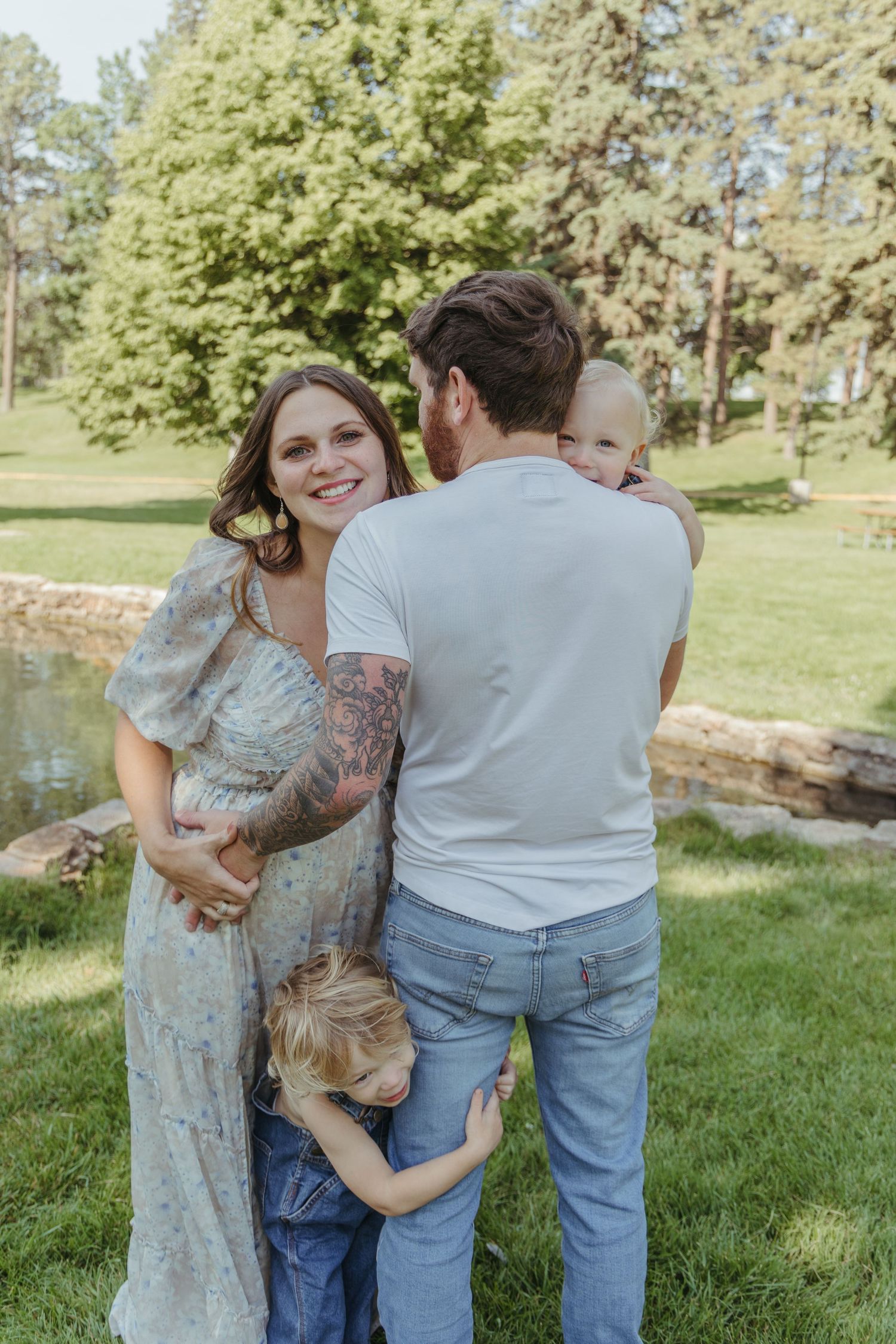 Family enjoying a tender moment together under trees in a grassy park.