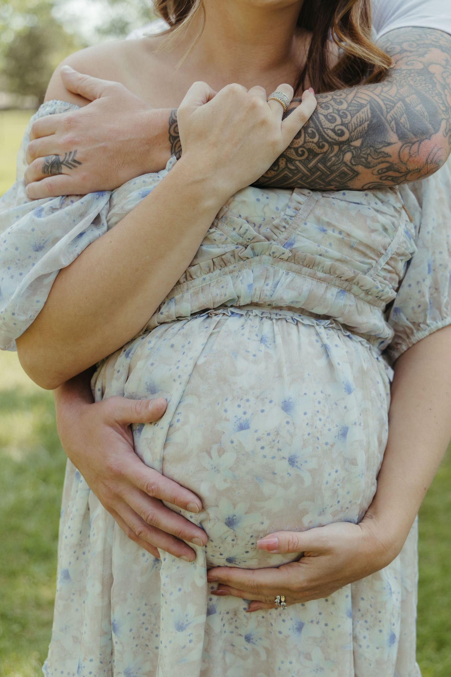 Close-up shots of hands cradling a pregnant belly in a floral dress.