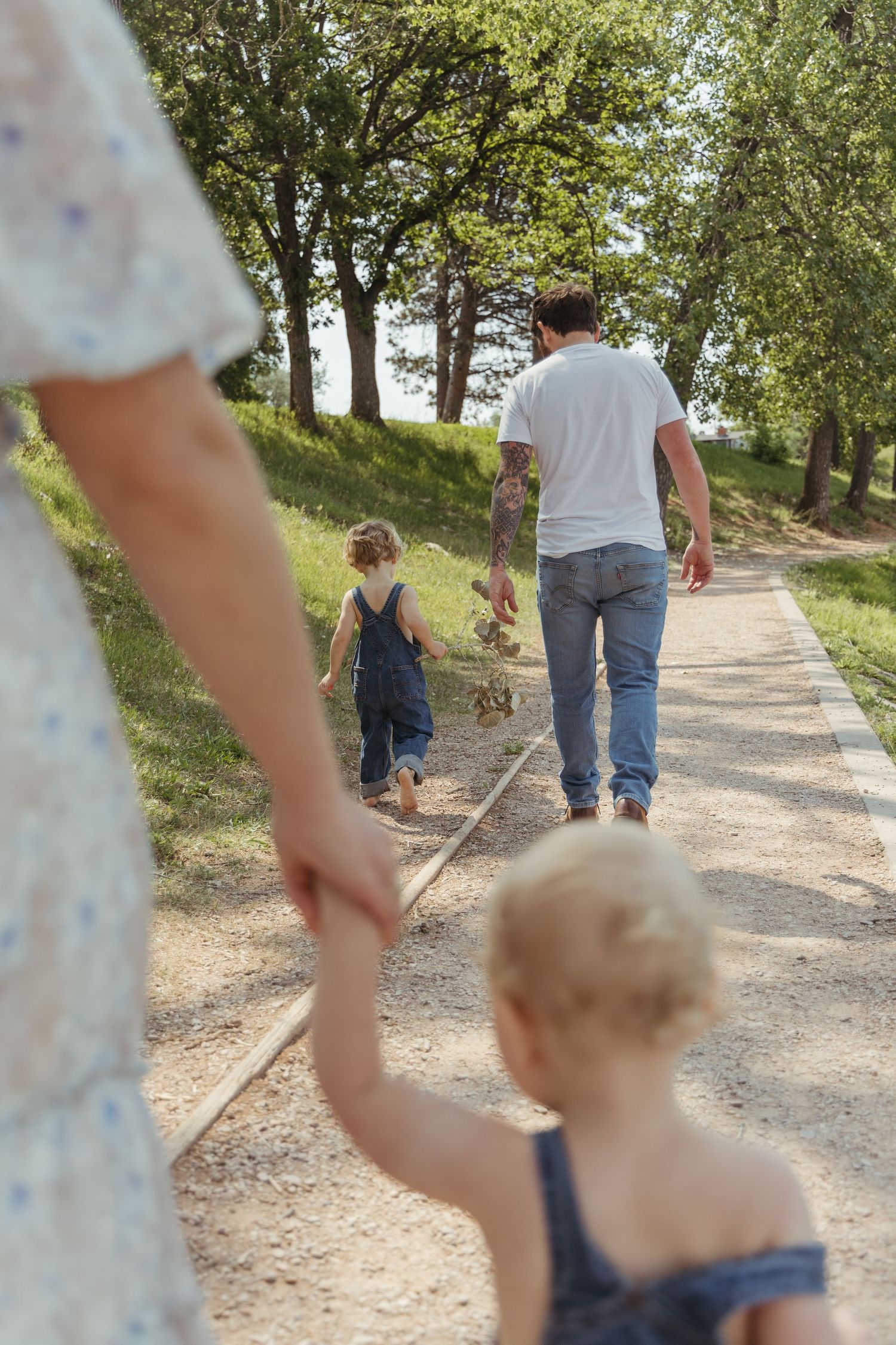 Family walking together on a winding dirt path through trees.