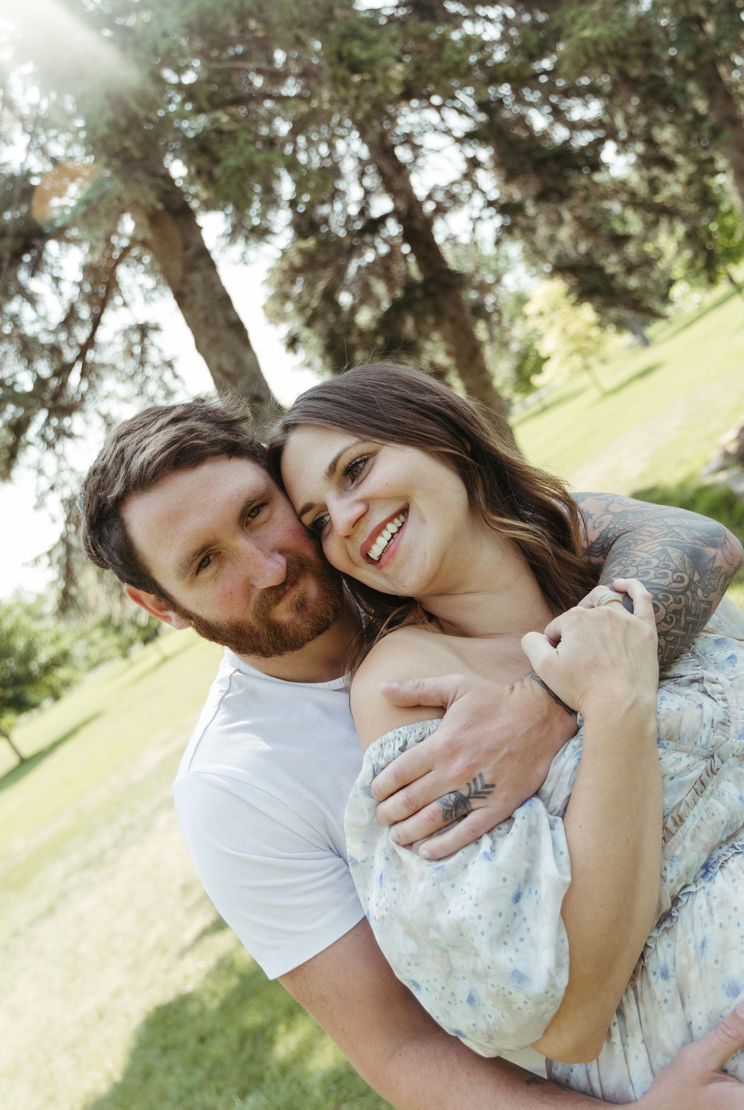 A romantic couple shares tender moments while posing against a natural outdoor backdrop.