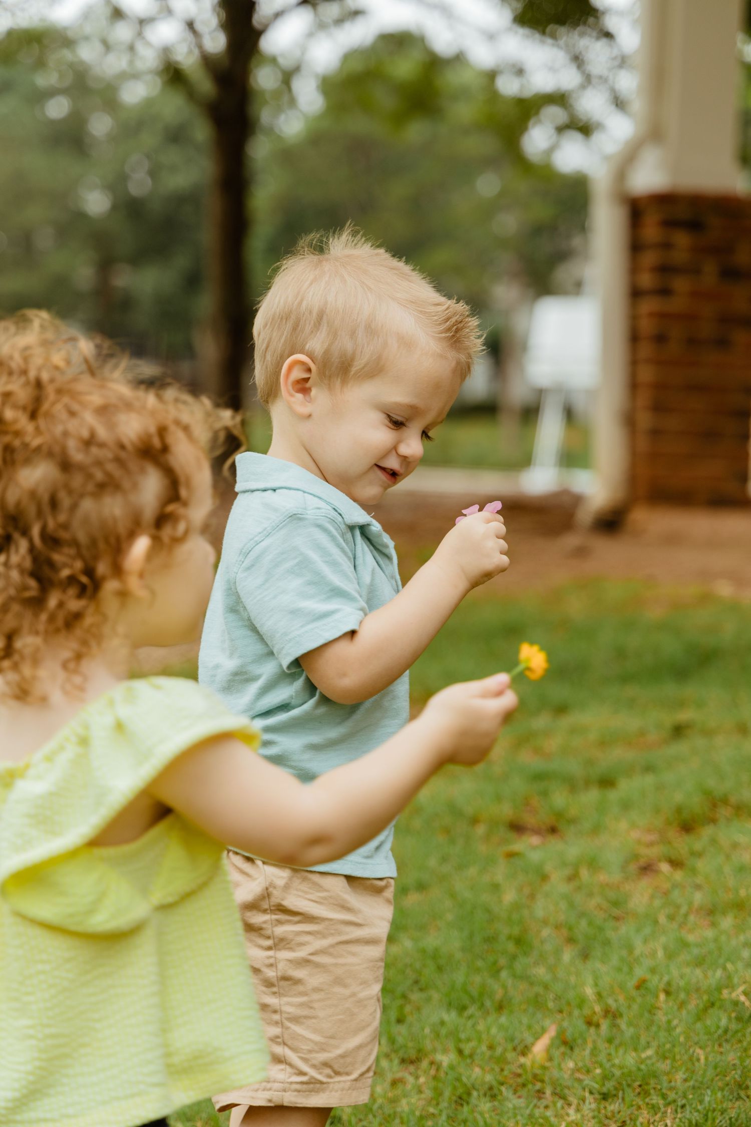 Children running and playing in a grassy yard near brick buildings.