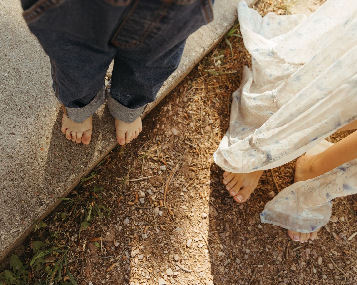 Close-up view of feet walking on a dirt and mulch covered path in an outdoor setting.