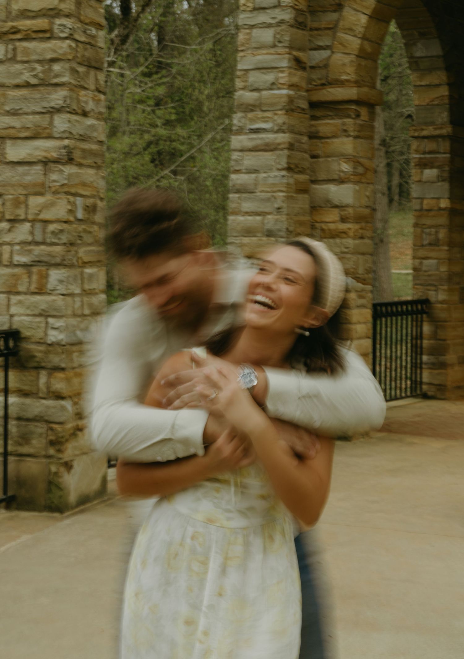 Playful couple spinning and dancing in a stone pavilion.