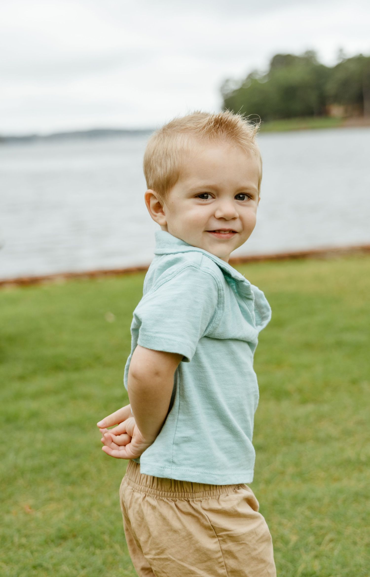 Toddler in mint green shirt and khaki pants playing by the waterfront.