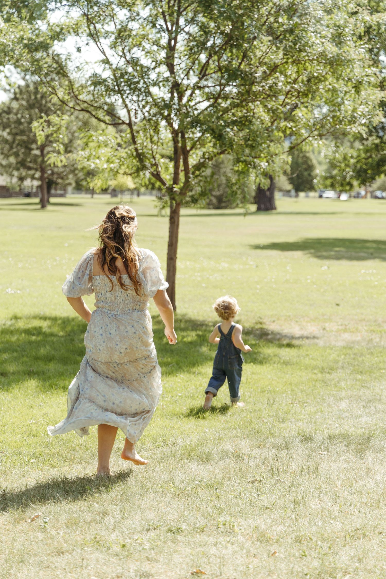 A playful outdoor photoshoot in a sunny park with trees and grass.