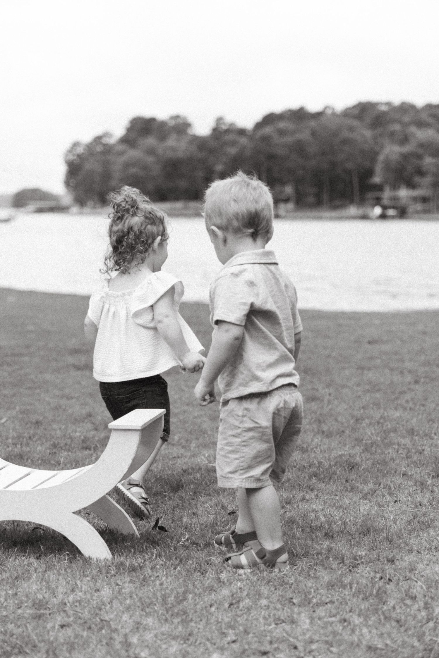 Children running with paper airplanes on grass in black and white.