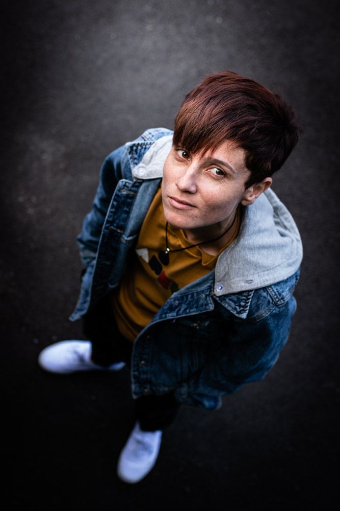 Artistic portrait shot from above showing person in denim jacket and mustard colored top.