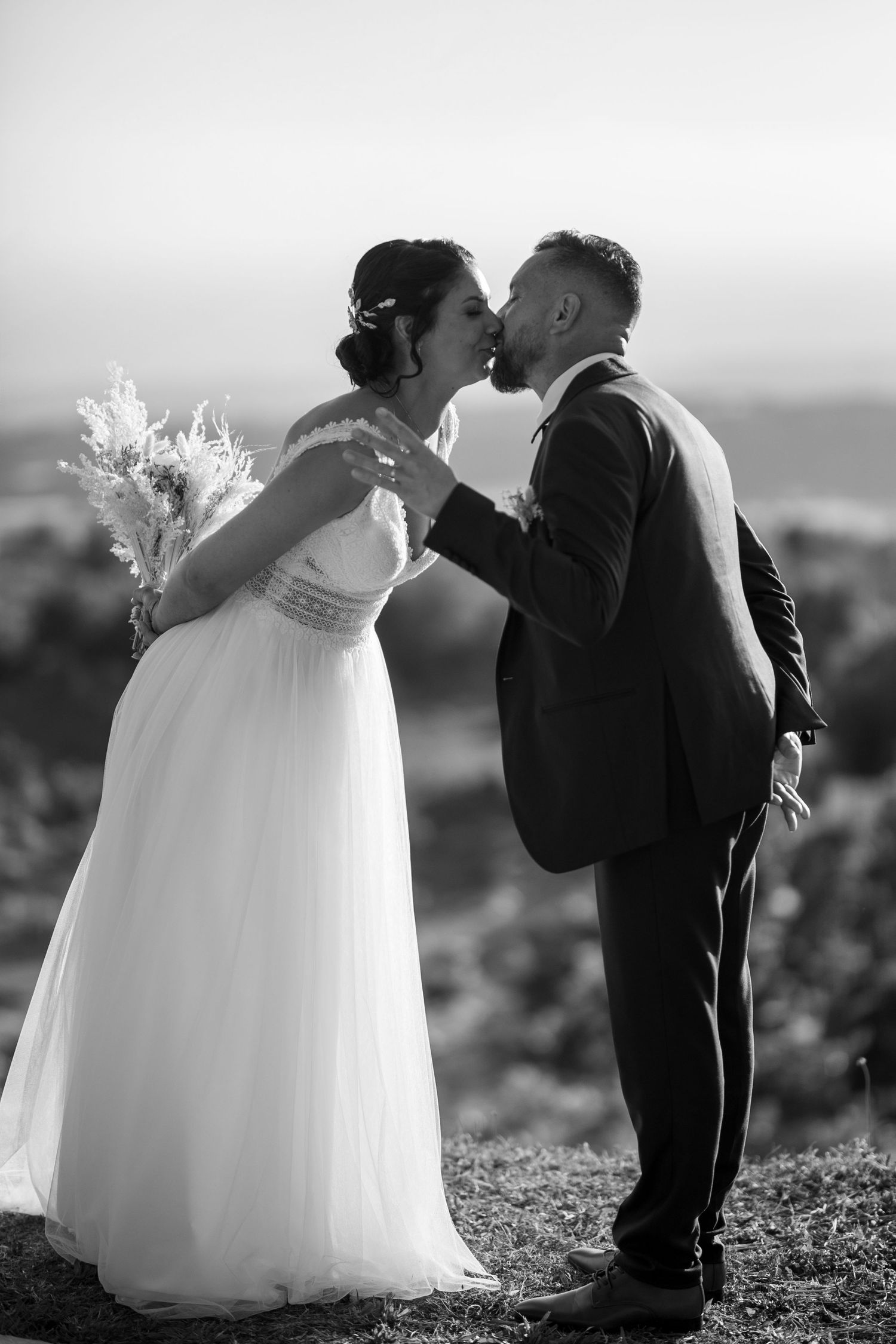 A romantic black and white portrait of newlyweds sharing an intimate moment against a scenic backdrop.