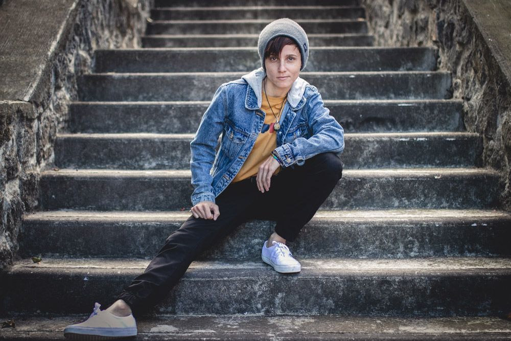 Person in denim jacket sitting on concrete stairs with a thoughtful pose.