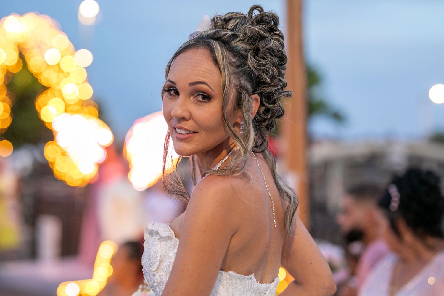 A bride in a strapless gown with an elegant updo hairstyle at sunset.