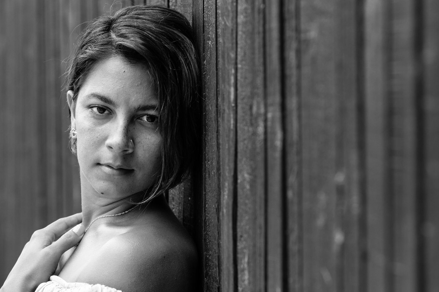 Artistic black and white portrait showing a dramatic side profile against wooden panels.