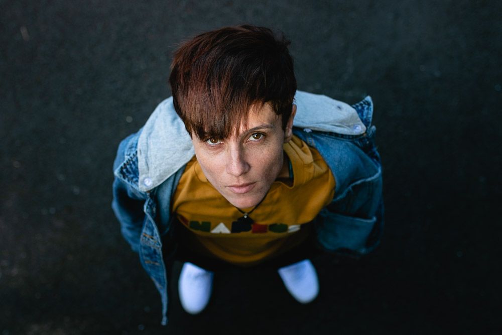 Person wearing yellow hoodie and denim jacket shot from above against dark background.