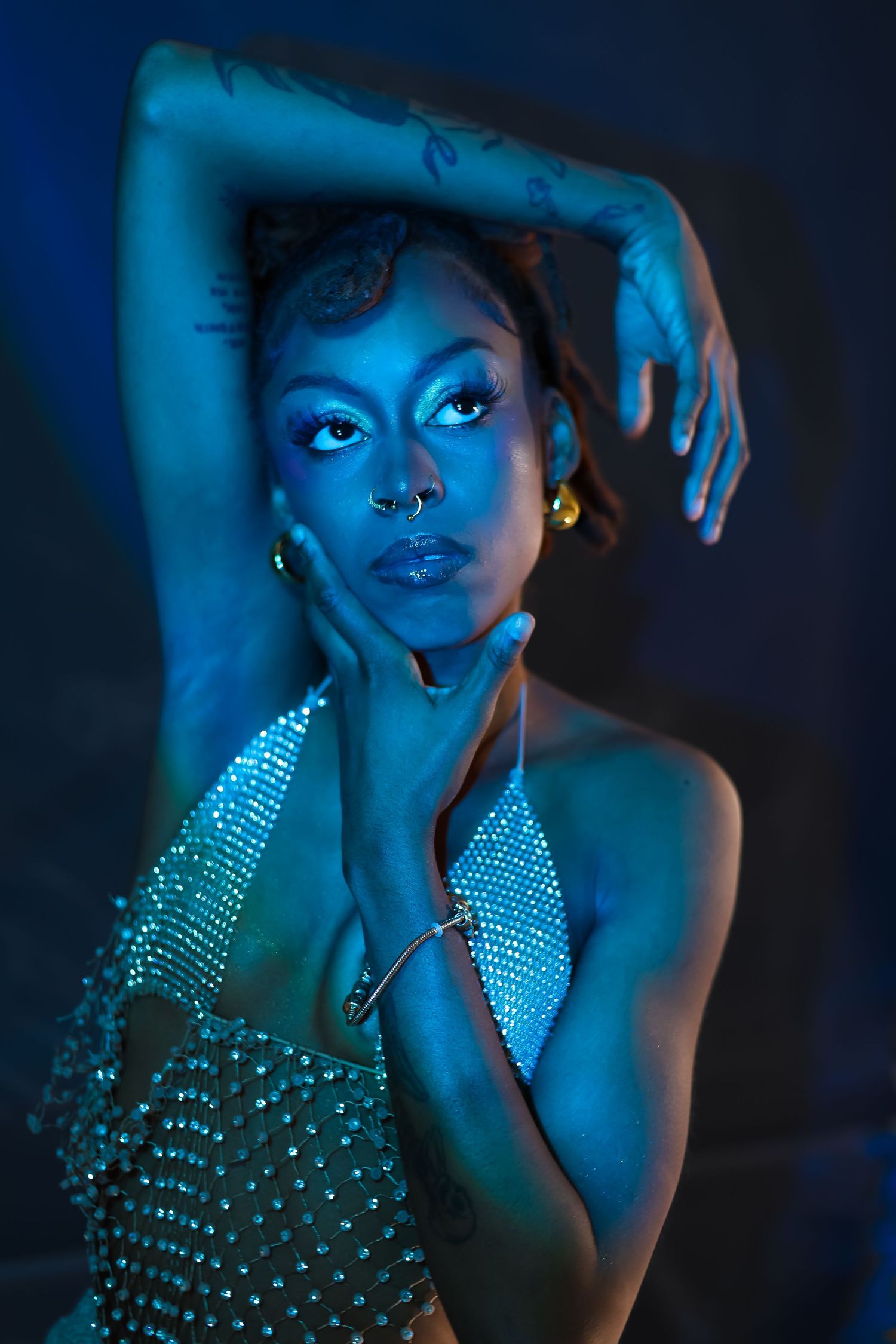Fashion portrait under blue lighting featuring rhinestone top and dramatic poses.