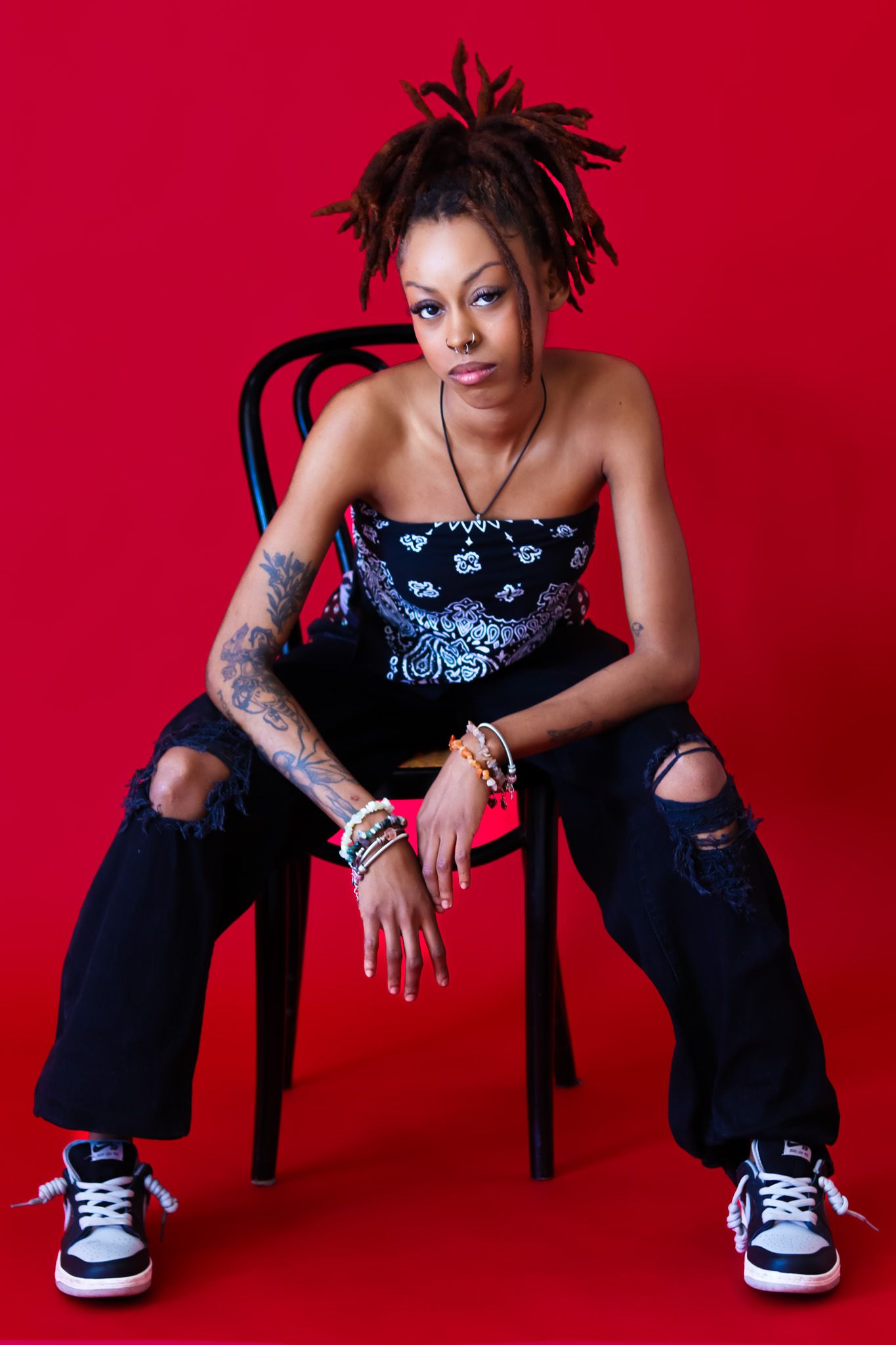 Stylish casual fashion poses against vibrant red background with sneakers and dark denim.