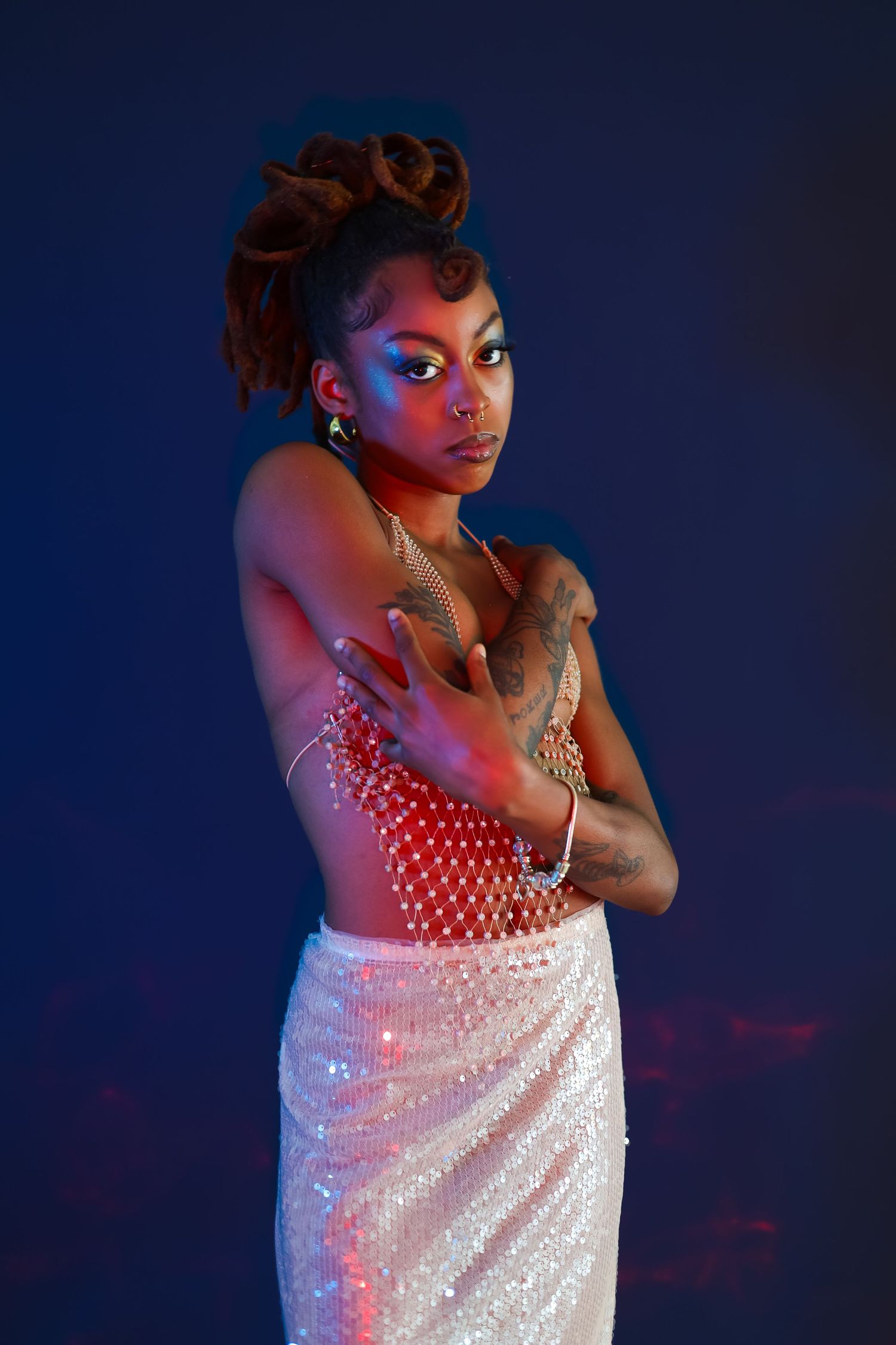 Glamour portrait with sparkly white dress against dark blue background.