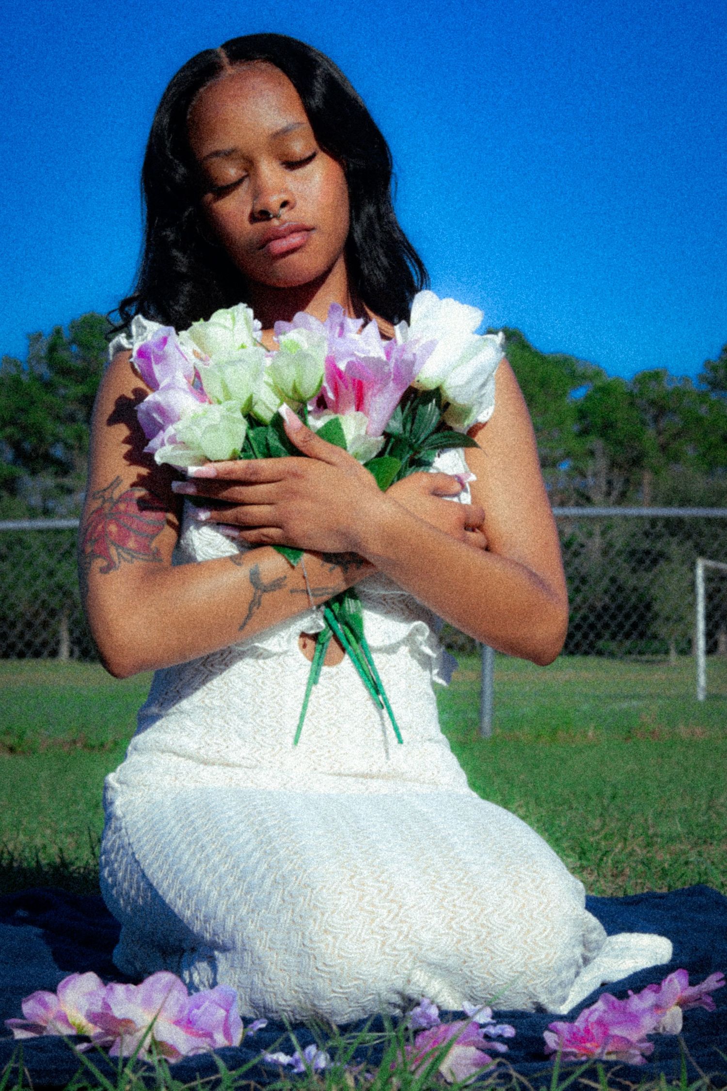 A white dress photoshoot with pink and white flowers on a sunny day.