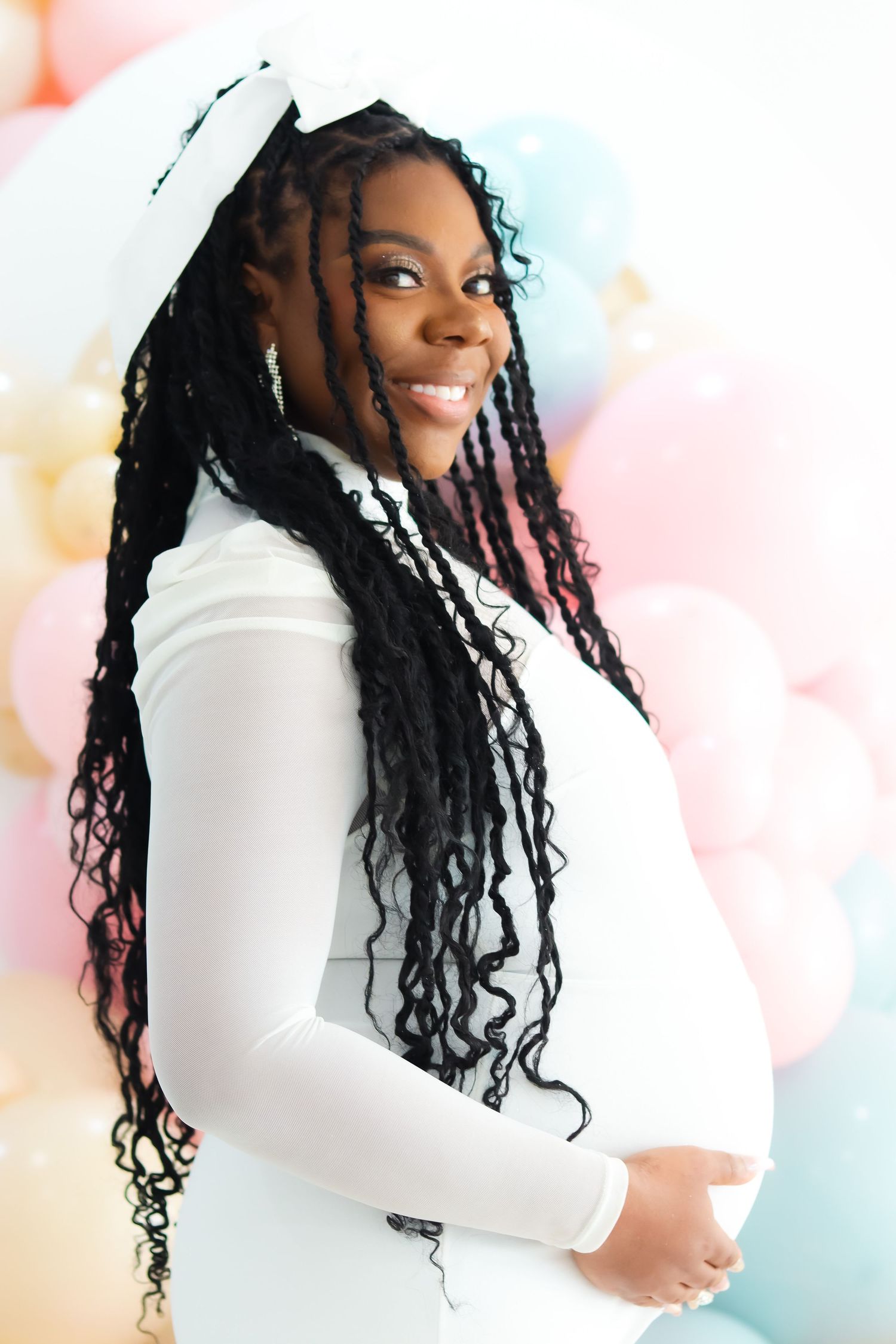 Bright and airy maternity portraits in white against pastel background.