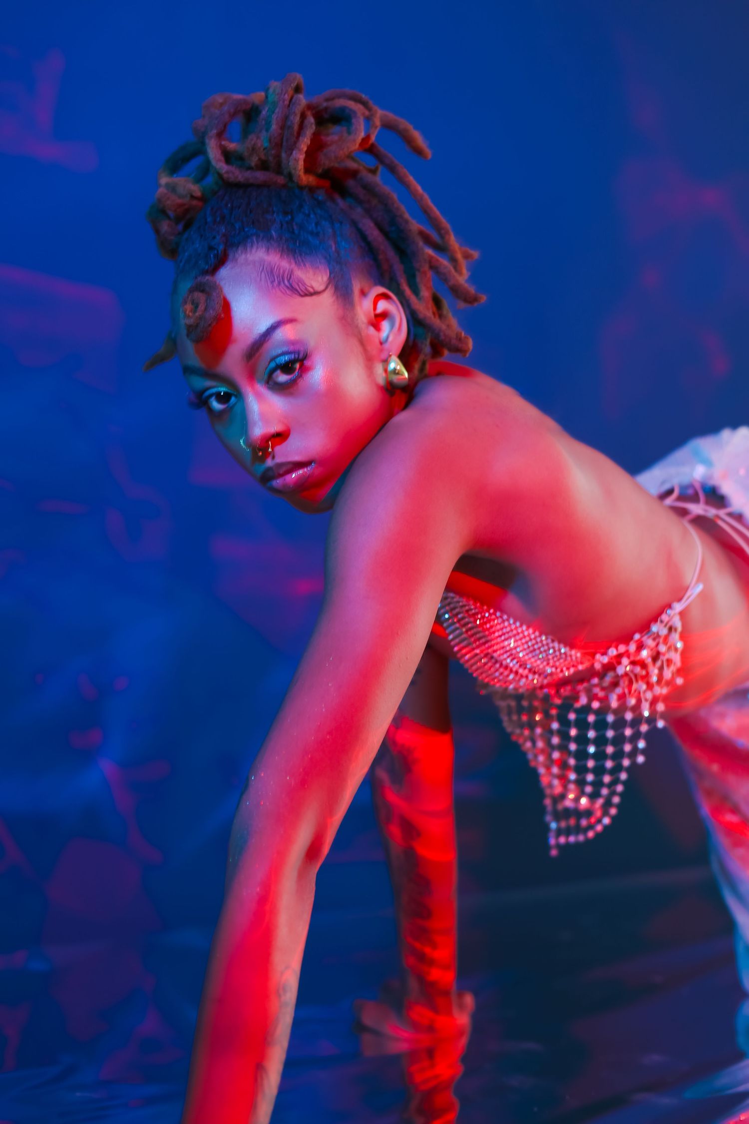 Fashion photo with dramatic pose and lighting effects in red and blue tones.