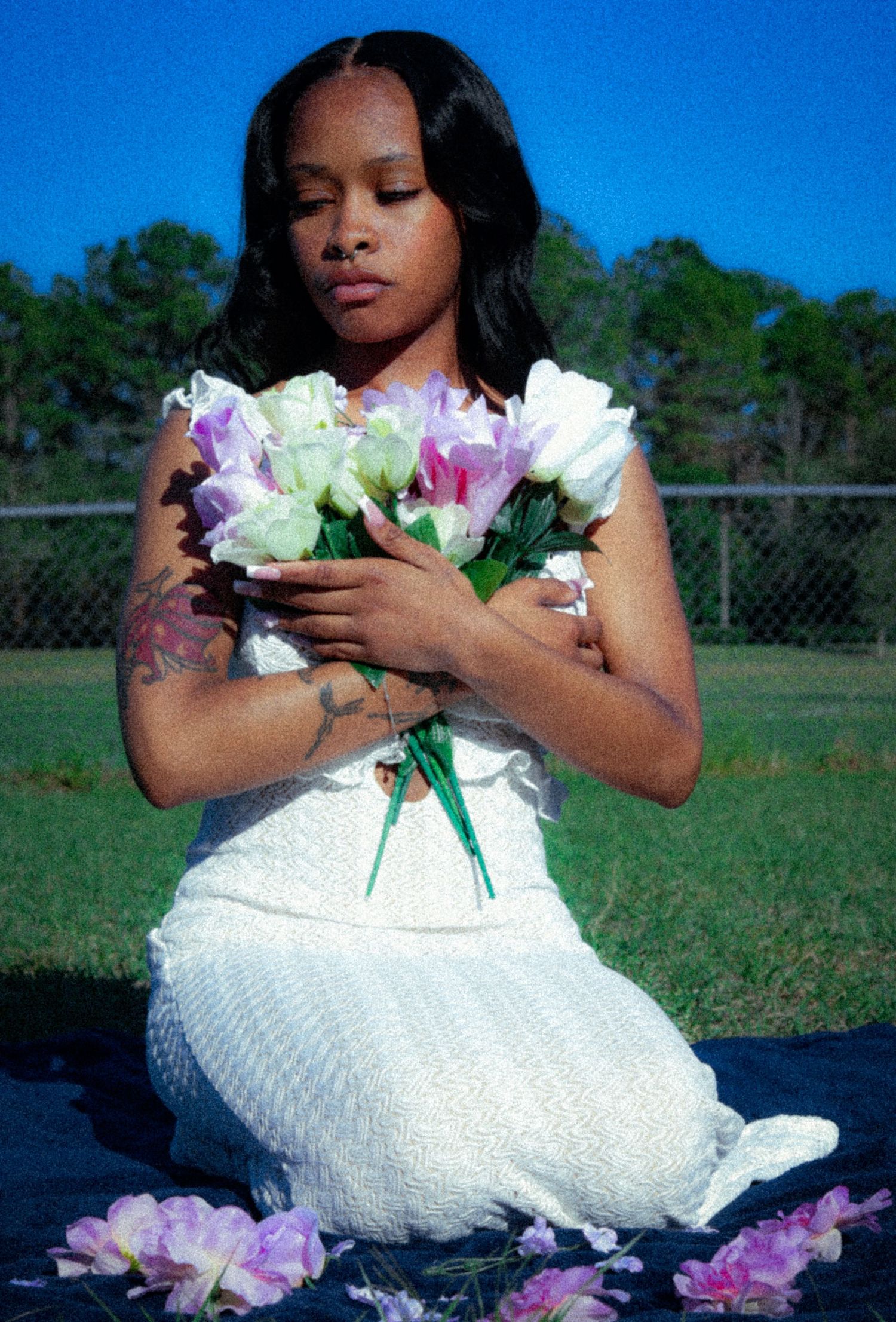 A white dress photoshoot with pink and white flowers on a grassy field.