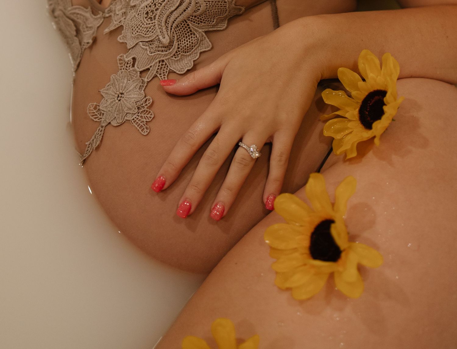 Artistic maternity photo with sunflowers and lace details on bare belly.
