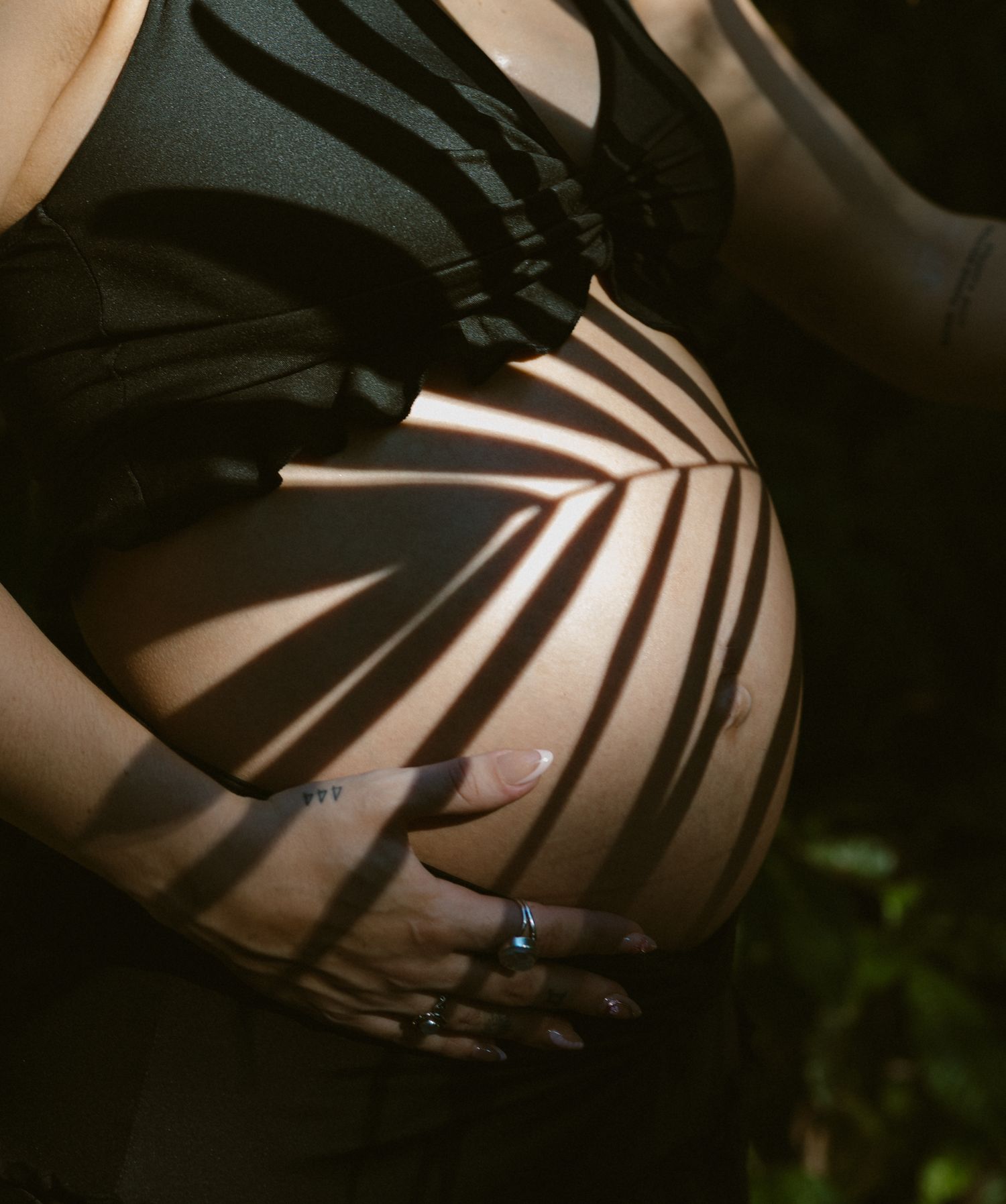 Dramatic black and white shadows cast zebra-like stripes on a torso in artistic boudoir photography.