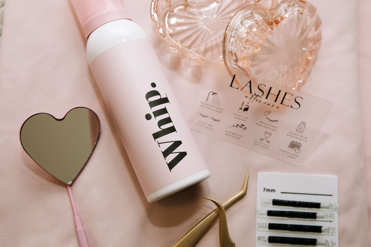 Professional beauty tools and treatment cards displayed on soft pink background.