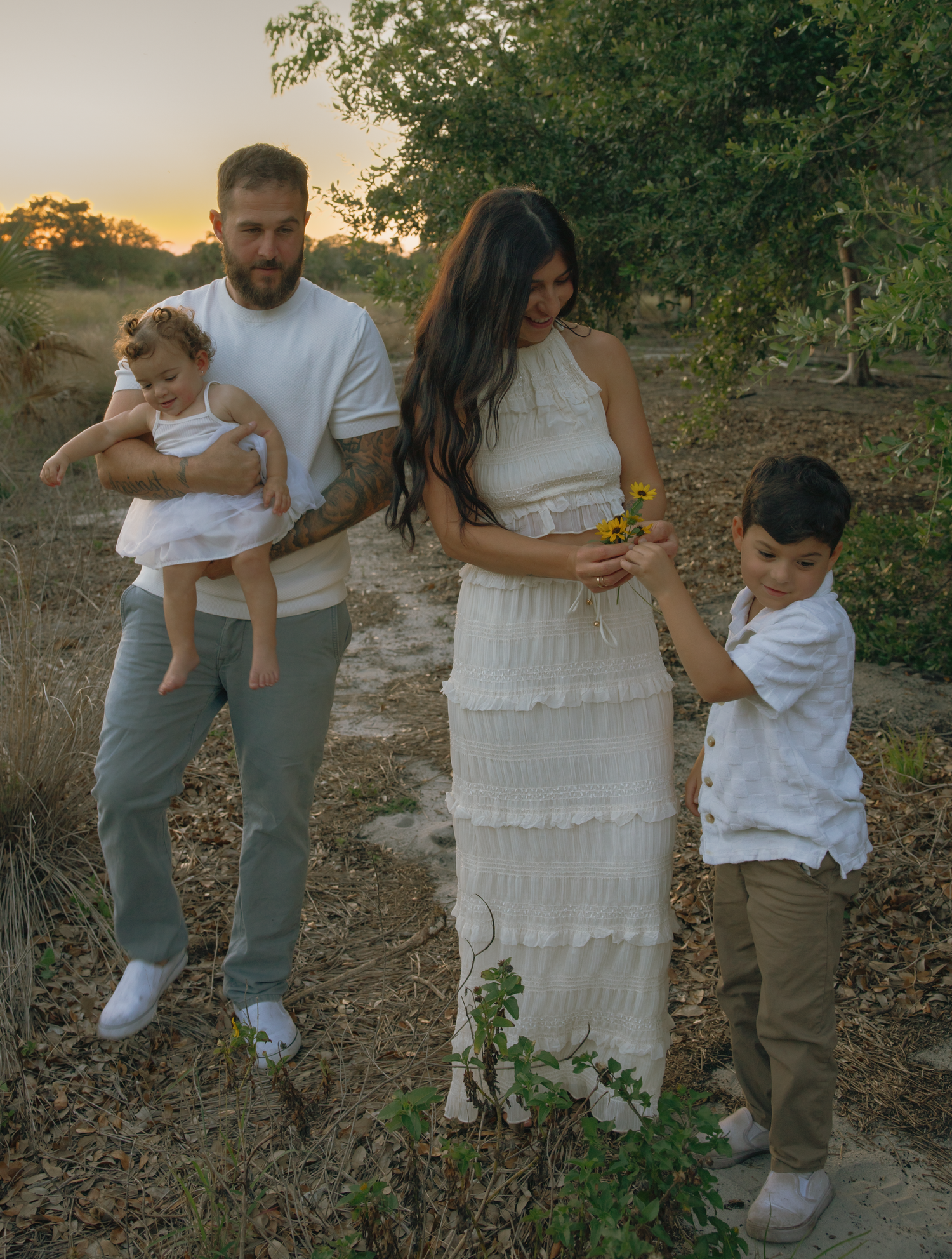 Candid family moments captured on rocky terrain with green foliage backdrop.