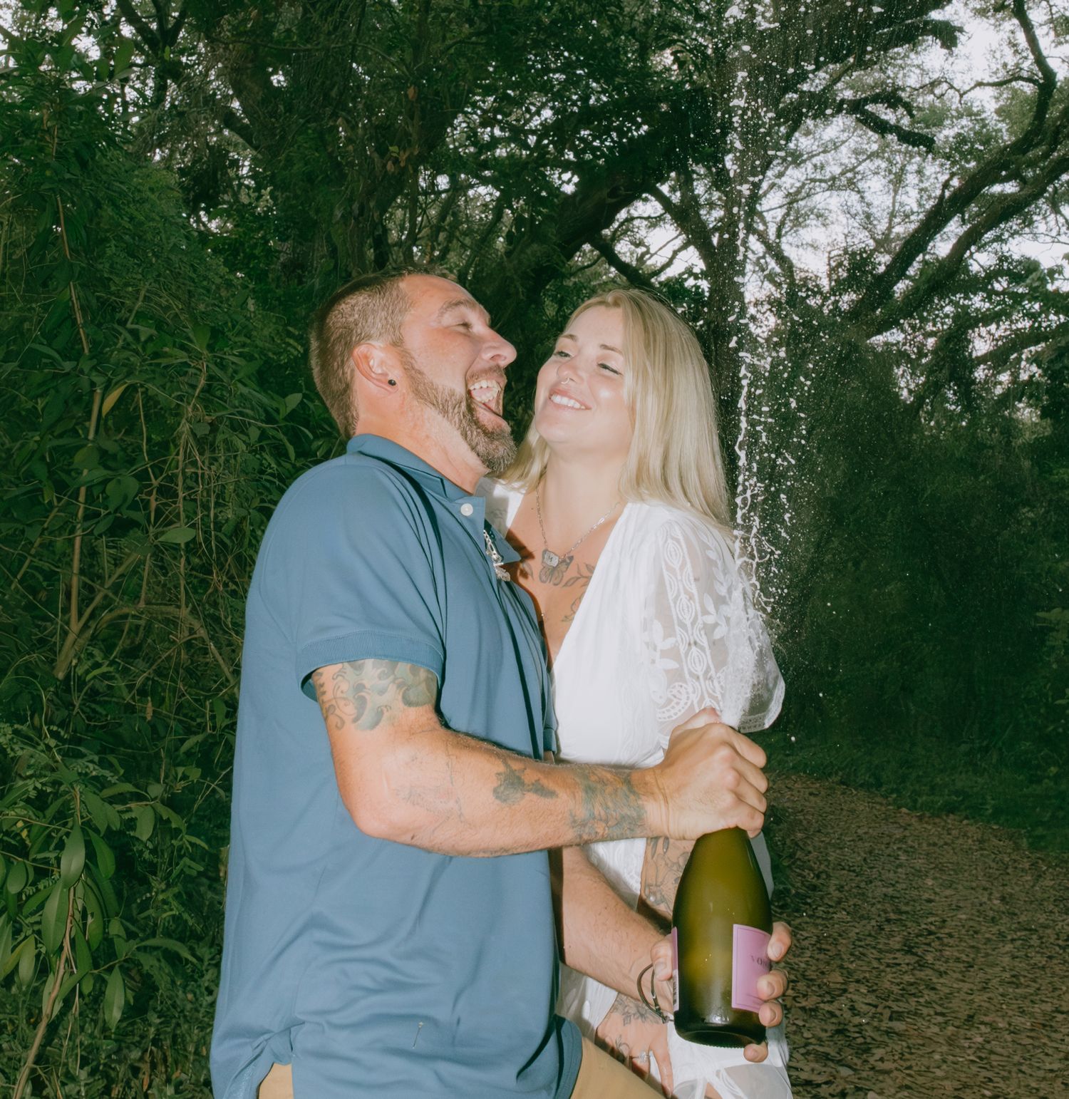 Joyful celebration moment between couple with champagne in woodland setting.
