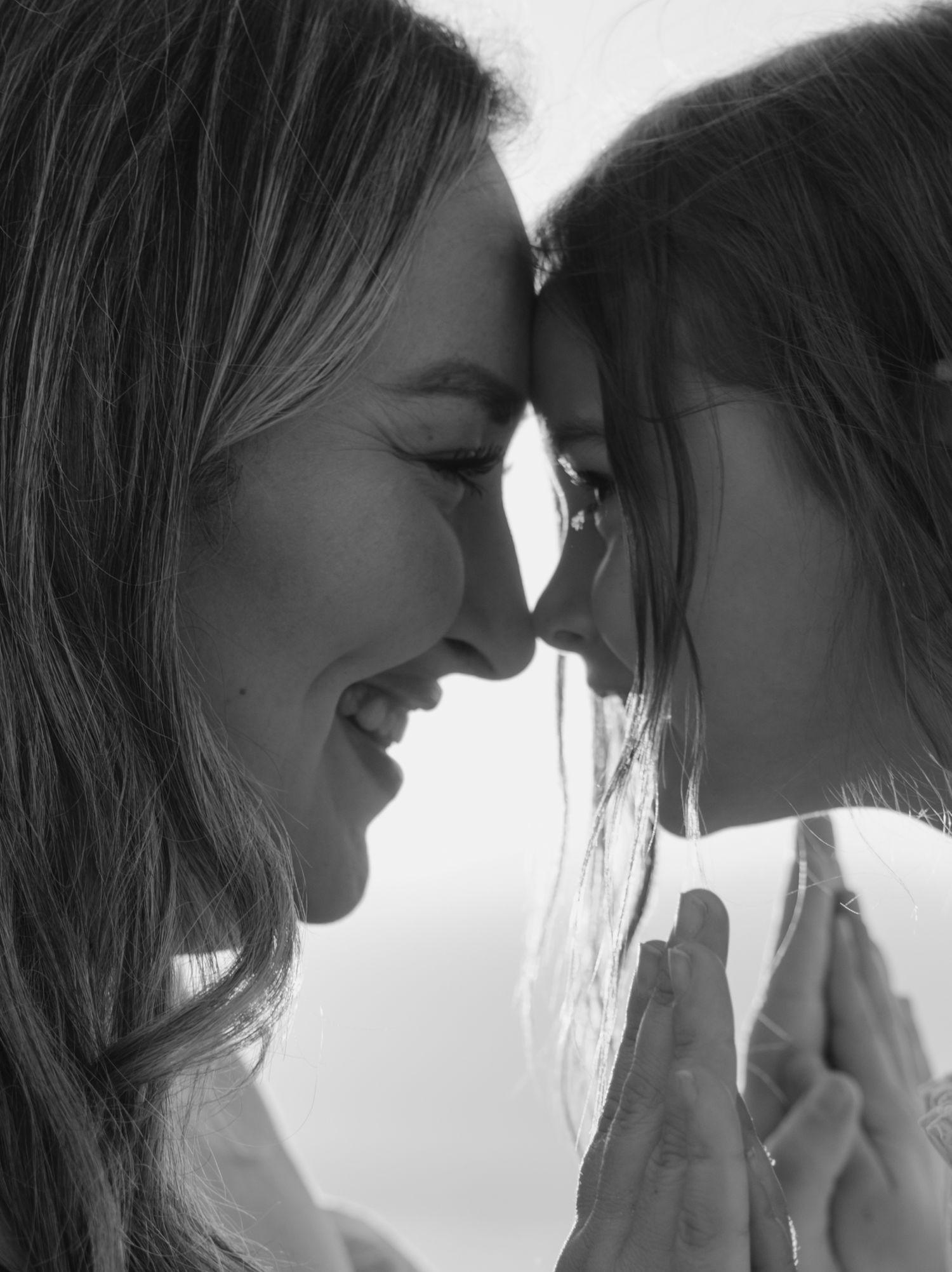 A black and white close-up portrait captures an intimate moment between two people.