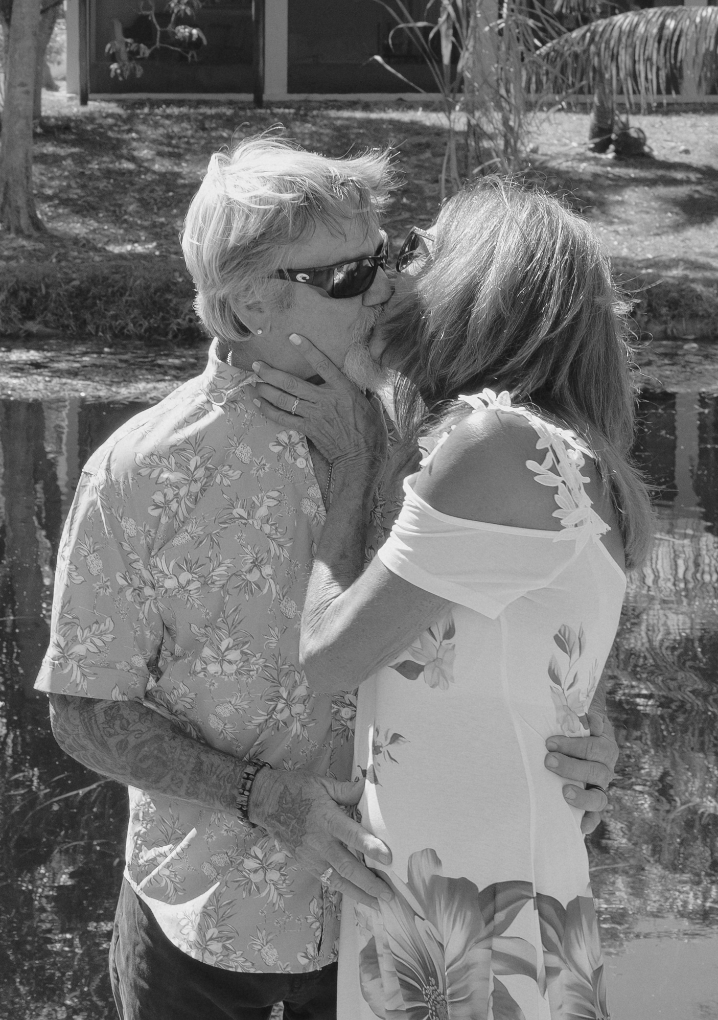 Two people in floral print outfits sharing an intimate moment in a garden setting.