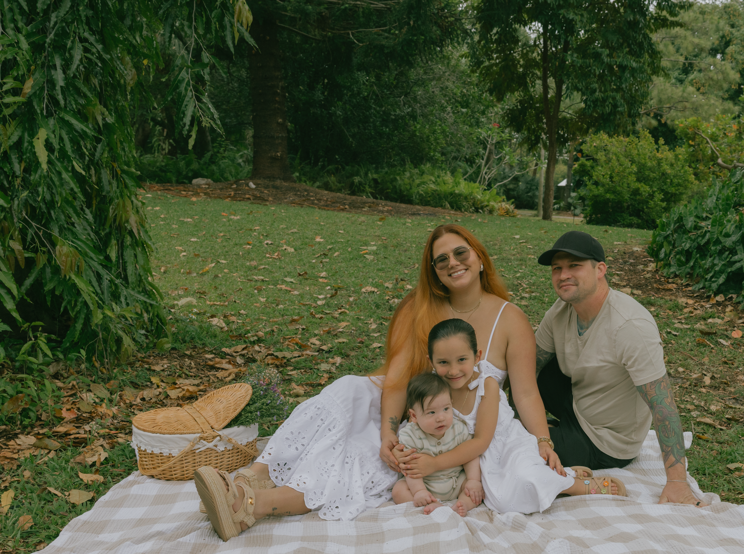 Panoramic view of family photo session on blanket in garden setting.