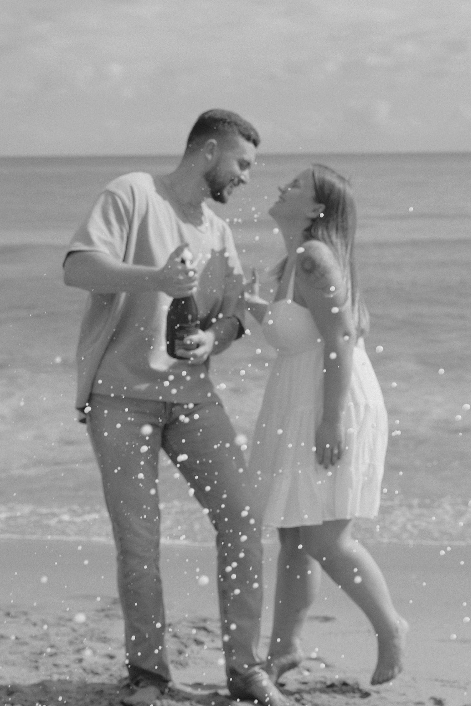 A couple shares a romantic moment on the beach in a black and white photo sequence.