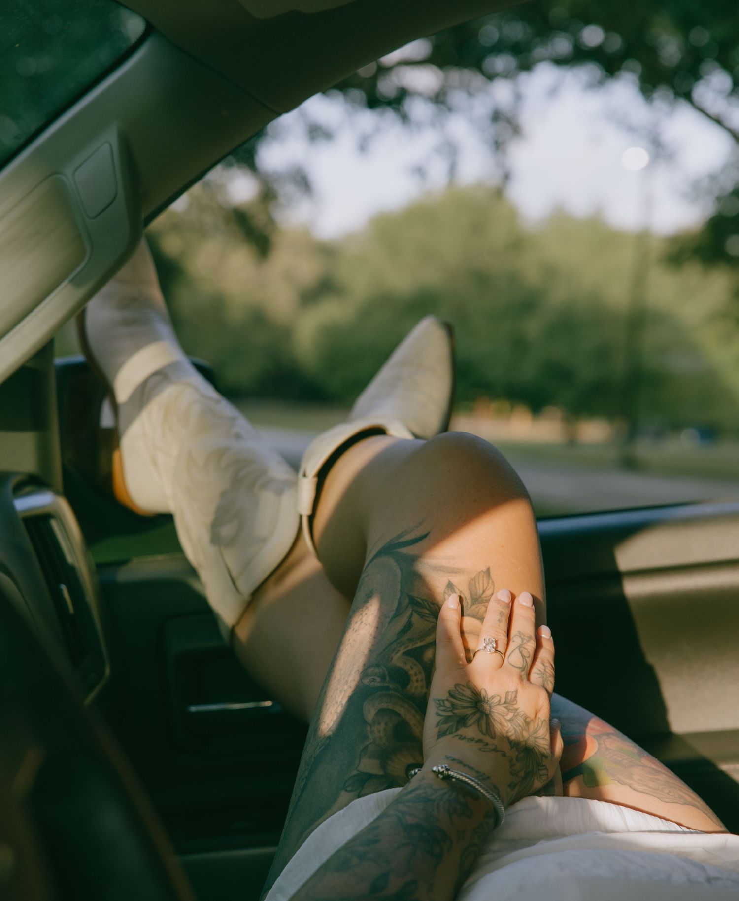 White boots and tattoos visible in the front seat of a car during a photo session.