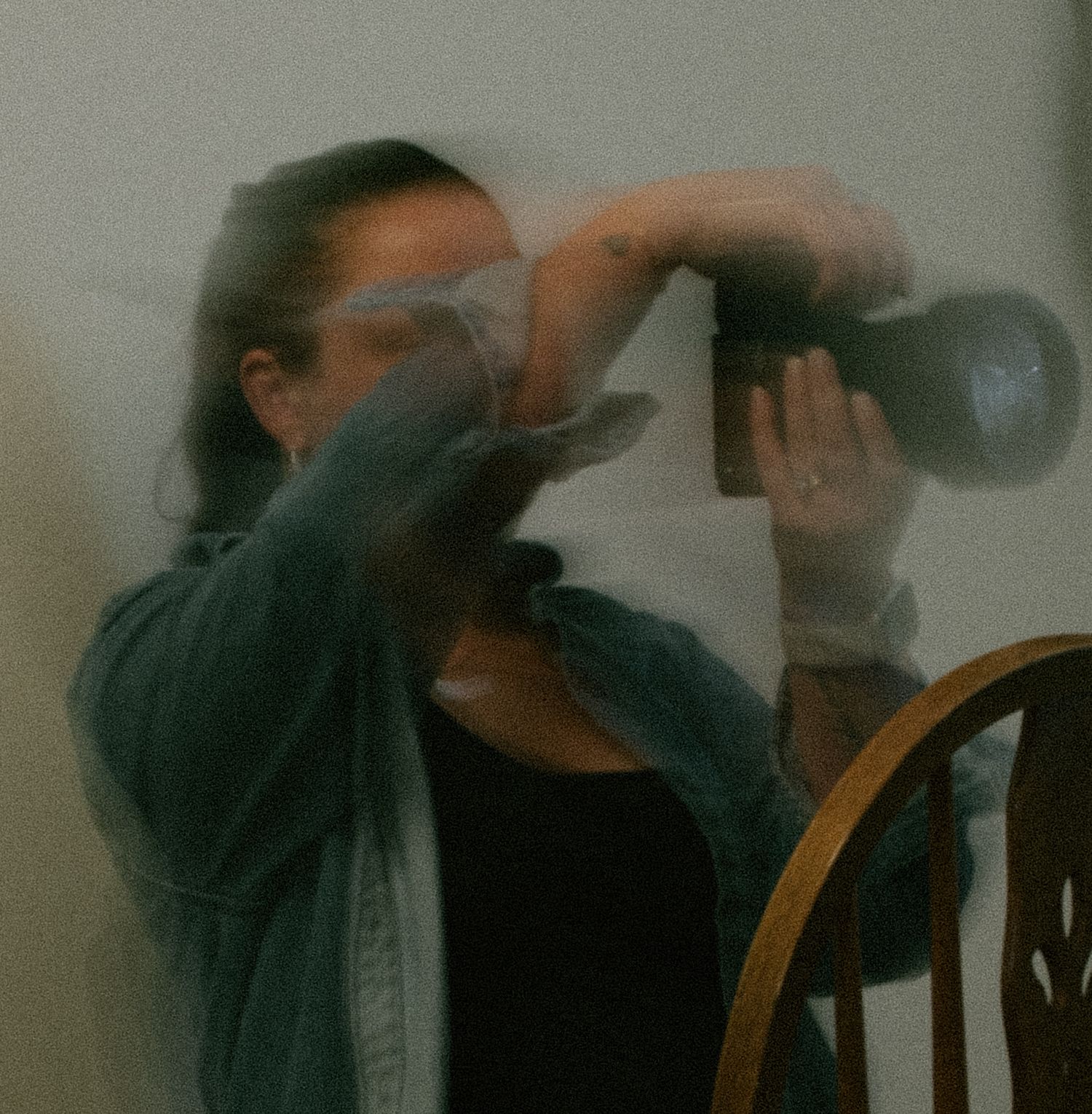 Time-lapse sequence showing a person drinking from a glass while seated in a wooden chair.