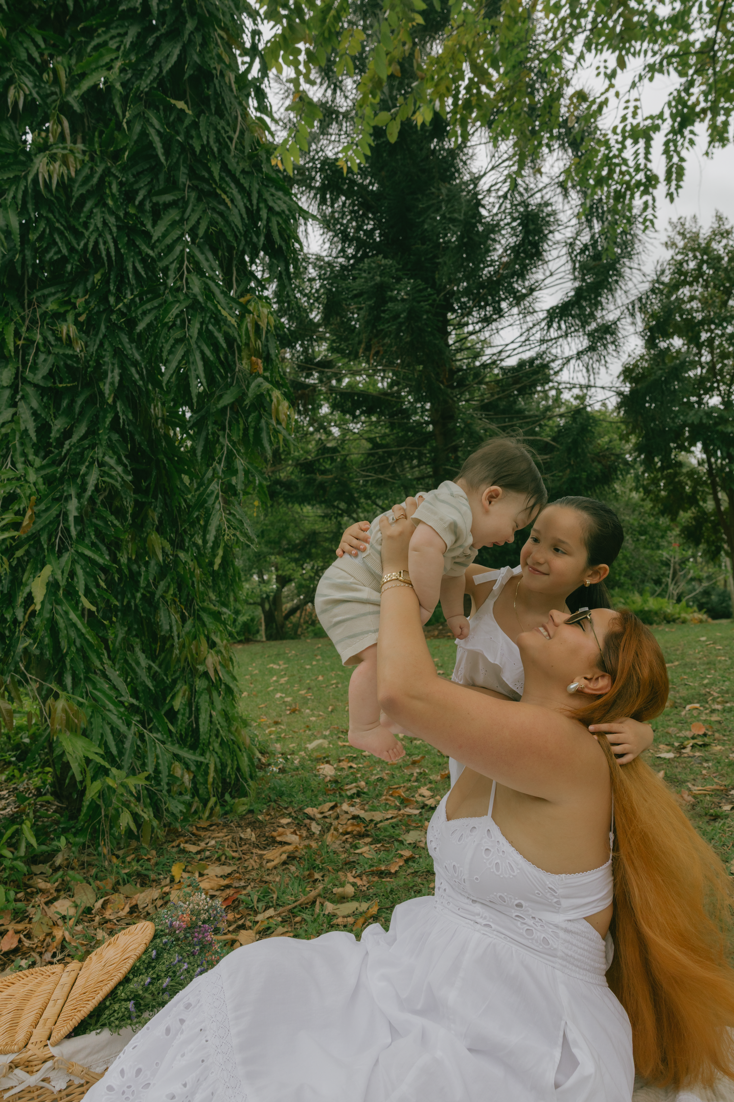 Tender moment between parent and child during outdoor picnic under willow trees.