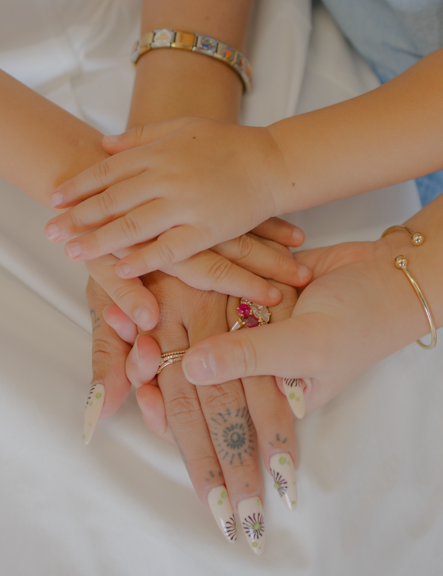 Close-up sequence of hands with delicate jewelry and painted nails showing different angles and poses against a white surface.