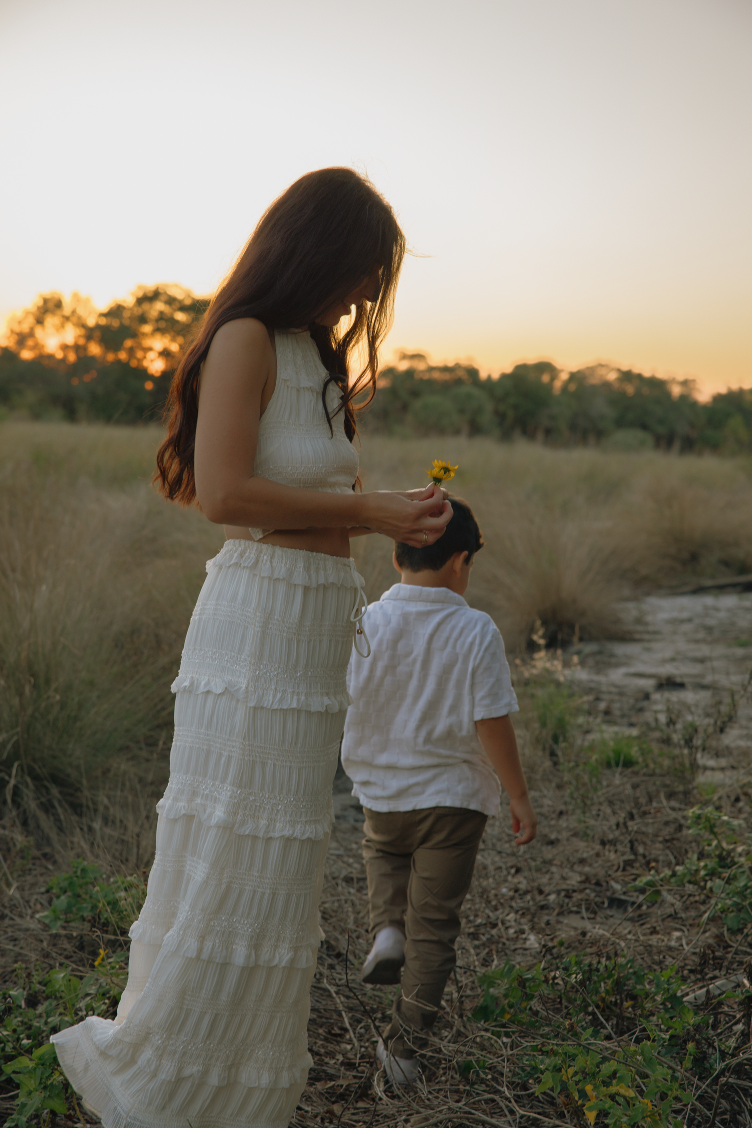 Family exploring natural landscape together at sunset against golden sky backdrop.