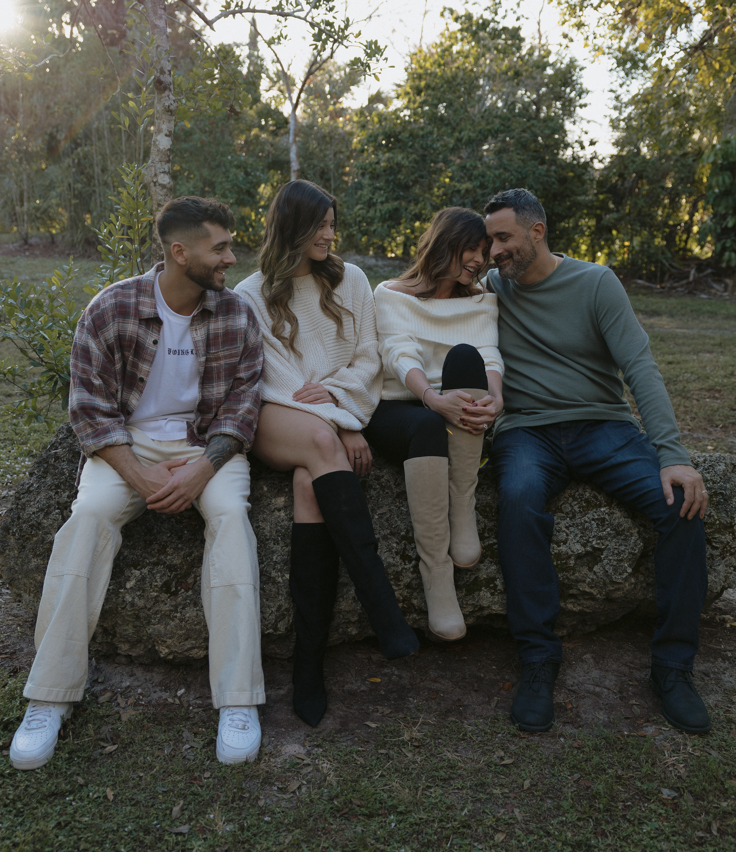 A group sits casually on a stone wall outdoors during sunset, creating a relaxed and candid moment.