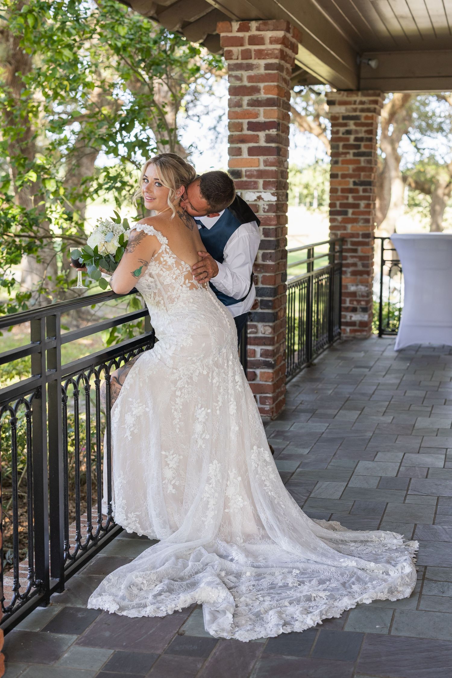 A couple shares an intimate moment on a brick porch with elegant railings during their wedding day.