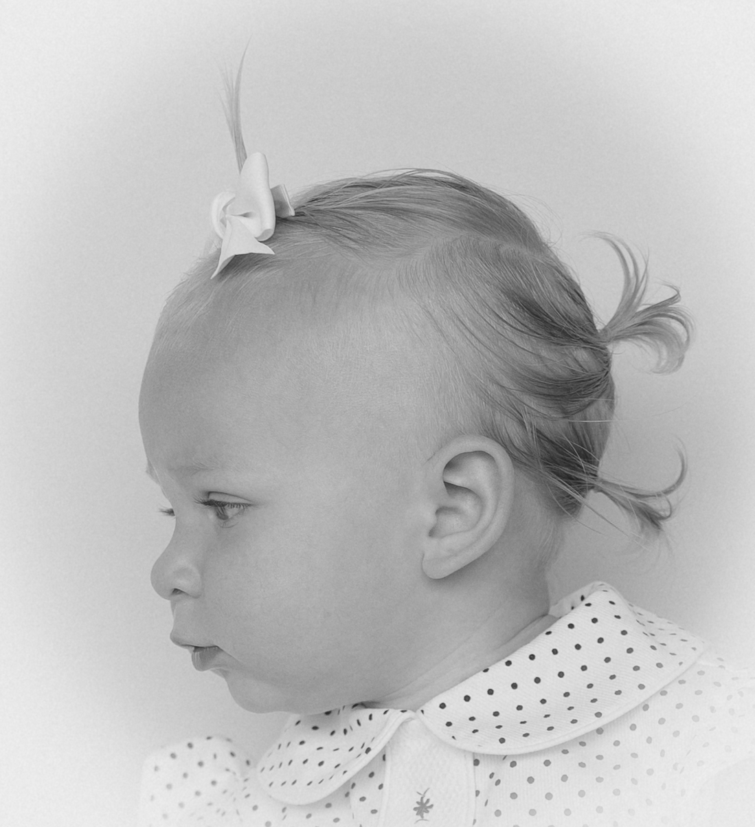 Black and white portrait series showing four profile views of a baby wearing polka dot clothing.